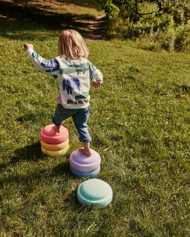 Child playing with colorful stepping stones on a grassy field