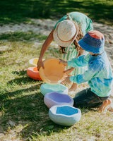 Two children playing with colorful sand toys on a sandy beach.