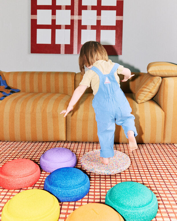 Child playing with colorful Stapelstein Rainbow Set on a checkered floor