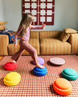 Child playing with colorful stepping stones on a checkered floor