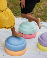 Colorful Stapelstein original rainbow pastel on a blanket with people stepping on them outdoors.